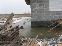 Zalanie powierzchni działki i wykopu pod drenaż wodami opadowymi - efekt braku rur spustowych z dachu budynku